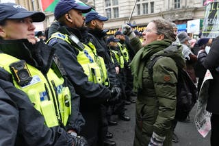 Police officers look on as people take part in a national march for Palestine on Whitehall